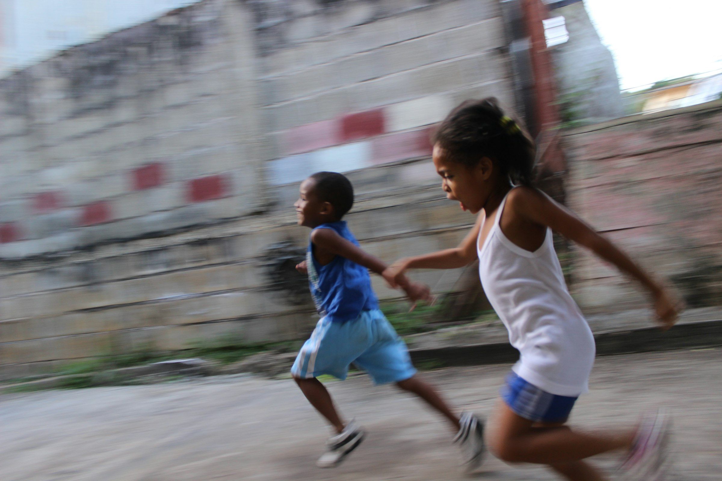 Two children running side by side on a street